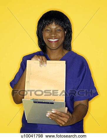 African-American mid-adult woman in medical uniform smiling reading chart. View Large Photo Image Stock Photo - African-American mid-adult woman in medical uniform smiling reading chart.. Fotosearch