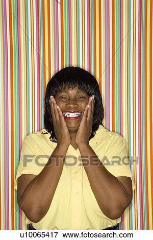 Stock Photo - African-American mid-adult woman looking surprised and happy.. Fotosearch