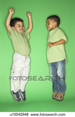 Stock Photo - Hispanic and African American male child jumping.. Fotosearch