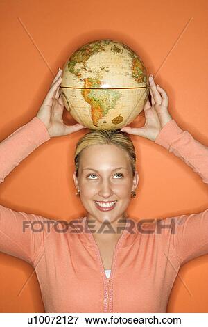 Portrait of Caucasian teen girl holding globe on her head smiling standing against orange background. View Large Photo Image Stock Photo - Portrait of Caucasian teen girl holding globe on her head smiling standing against orange background.. Fotosearch