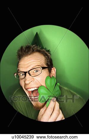 Vignette of excited adult Caucasian man on green background wearing Saint Patricks Day hat and holding shamrock. View Large Photo Image Stock Photo - Vignette of excited adult Caucasian man on green background wearing Saint Patricks Day hat and holding shamrock.. Fotosearch