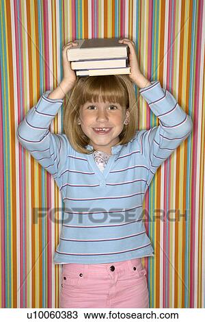 Stock Image - Caucasian female child balancing books on head.. Fotosearch
