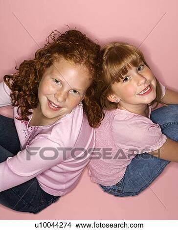 Picture - Caucasian female children sitting back to back.. Fotosearch