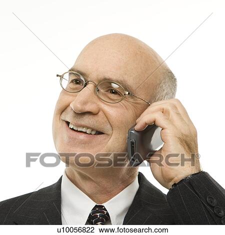 Stock Image - Caucasian middle-aged businessman talking on cellphone smiling against white background.. Fotosearch