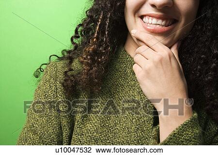 Close-up of smiling young Caucasian woman with hand on chin on green background wearing green clothing. View Large Photo Image Stock Image - Close-up of smiling young Caucasian woman with hand on chin on green background wearing green clothing.. Fotosearch
