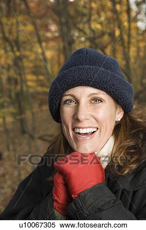 Stock Photography - Head and shoulder portrait of smiling Caucasian woman in hat and gloves in woods.. Fotosearch