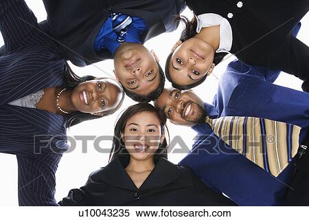 Stock Photography - Low angle portrait of multi-ethnic business group of men and women in huddle looking at viewer.. Fotosearch