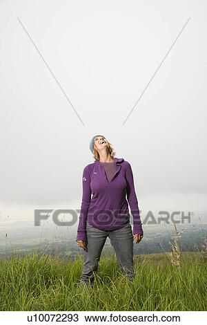 Middle-aged Caucasian woman standing alone in field with head back laughing. View Large Photo Image Stock Image - Middle-aged Caucasian woman standing alone in field with head back laughing.. Fotosearch