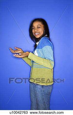 Stock Image - Portrait of African-American teen girl with palms turned upward.. Fotosearch