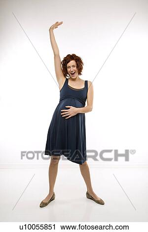 Portrait of Caucasion mid-adult attractive pregnant woman standing with one hand on belly and other arm in air looking at viewer and smiling. View Large Photo Image Stock Image - Portrait of Caucasion mid-adult attractive pregnant woman standing with one hand on belly and other arm in air looking at viewer and smiling.. Fotosearch