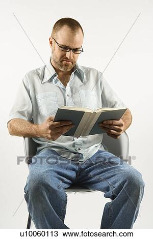 Caucasian man sitting in chair reading book against white background. View Large Photo Image Stock Image - Caucasian man sitting in chair reading book against white background.. Fotosearch