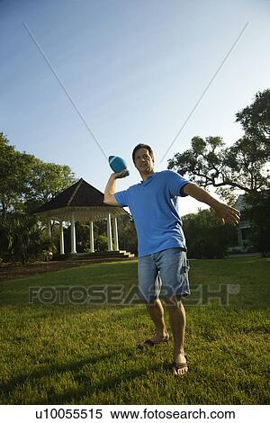 Stock Photography - Caucasian mid-adult man throwing football.. Fotosearch
