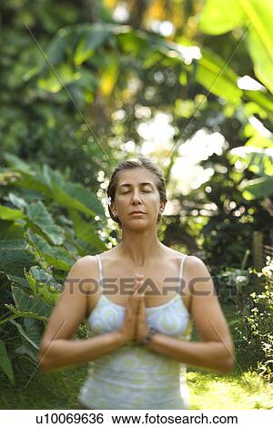 Stock Photograph - Caucasian mid-adult woman meditating.. Fotosearch