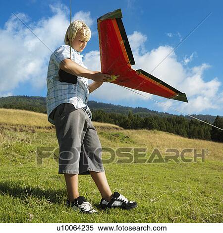 Stock Photography - Pre-teen Caucasian male preparing to fly remote controlled airplane on grassy knoll.. Fotosearch