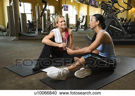 Stock Image - Prime adult Caucasian female with personal trainer at gym.. Fotosearch