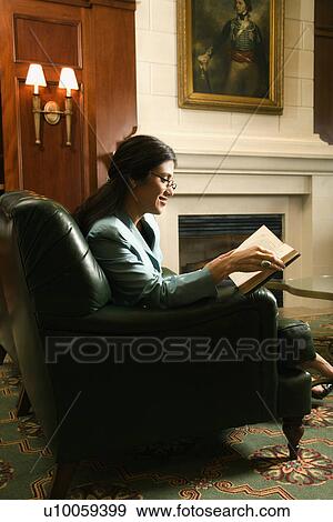 Stock Photo - Prime adult Hispanic female sitting and reading.. Fotosearch