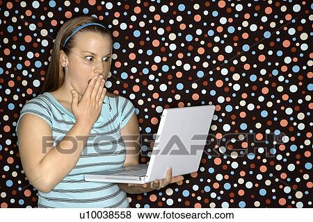 Young Caucasian woman holding laptop looking shocked. View Large Photo Image Stock Photo - Young Caucasian woman holding laptop looking shocked.. Fotosearch