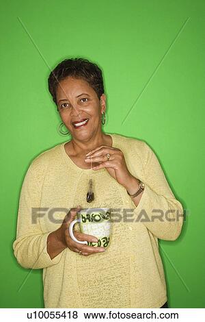 Stock Photo - African American female mature adult dipping tea bag in mug.. Fotosearch