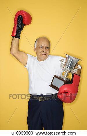 Caucasian mature adult male holding trophy and wearing boxing gloves. View Large Photo Image Stock Image - Caucasian mature adult male holding trophy and wearing boxing gloves.. Fotosearch