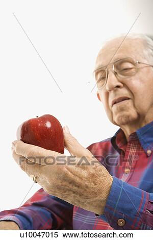 Caucasion elderly man looking at red apple in his hand. View Large Photo Image Stock Photography - Caucasion elderly man looking at red apple in his hand.. Fotosearch