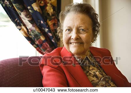 Stock Image - Elderly Caucasian woman by window at retirement community center.. Fotosearch
