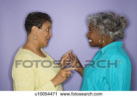Stock Image - Mature adult African American female pointing at eachother.. Fotosearch