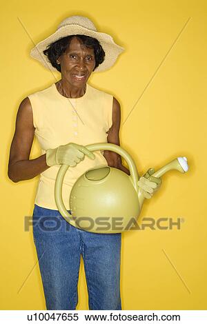 Mature adult African American female holding watering can. View Large Photo Image Stock Photography - Mature adult African American female holding watering can.. Fotosearch