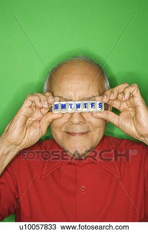Stock Image - Mature adult Caucasian male holding pill organizer.. Fotosearch