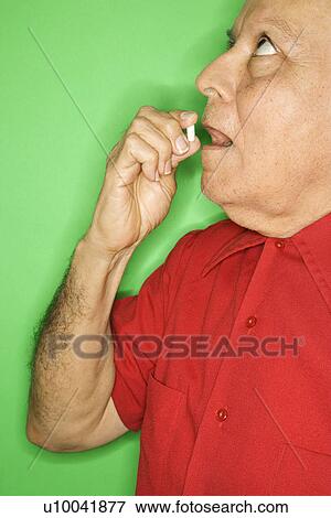 Mature adult Caucasian male putting pill in mouth. View Large Photo Image Stock Photo - Mature adult Caucasian male putting pill in mouth.. Fotosearch