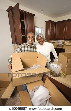 Stock Photo - Portrait of middle-aged African-American couple with moving boxes in kitchen.. Fotosearch