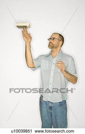 Caucasian man balancing book on fingers standing against white background. View Large Photo Image Stock Image - Caucasian man balancing book on fingers standing against white background.. Fotosearch