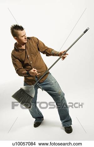 Caucasian man with mohawk playing broom like guitar against white background. View Large Photo Image Picture - Caucasian man with mohawk playing broom like guitar against white background.. Fotosearch
