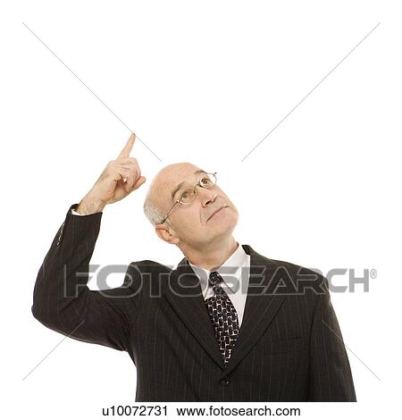Stock Image - Caucasian middle-aged businessman looking and pointing up standing against white background.. Fotosearch