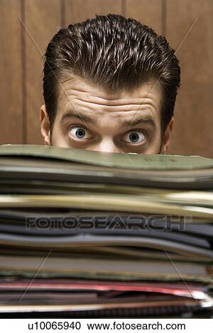 Caucasion mid-adult retro businessman peering with wide eyes over a tall stack of folders. View Large Photo Image Stock Image - Caucasion mid-adult retro businessman peering with wide eyes over a tall stack of folders.. Fotosearch