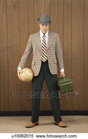 Stock Photography - Mid-adult Caucasian male holding a globe and carrying luggage.. Fotosearch
