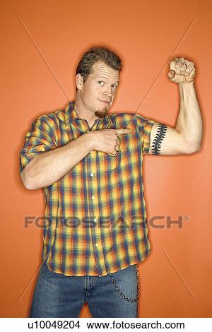 Picture - Portrait of adult Caucasian man on orange background flexing and showing off his arm muscle.. Fotosearch