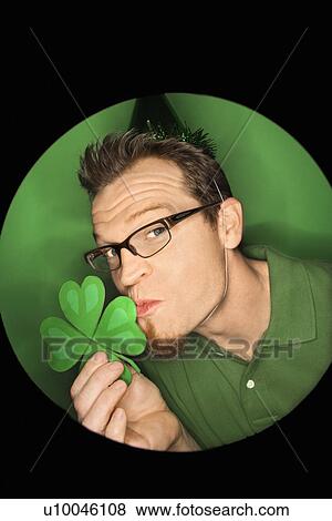 Vignette of adult Caucasian man on green background wearing Saint Patricks Day hat and kissing shamrock. View Large Photo Image Stock Photo - Vignette of adult Caucasian man on green background wearing Saint Patricks Day hat and kissing shamrock.. Fotosearch