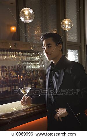 Prime adult Asian male standing at bar with cocktail. View Large Photo Image Stock Photograph - Prime adult Asian male standing at bar with cocktail.. Fotosearch