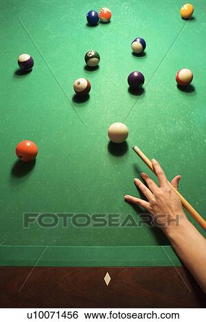 Stock Photograph - Woman's hand preparing to hit pool ball while playing billiards.. Fotosearch