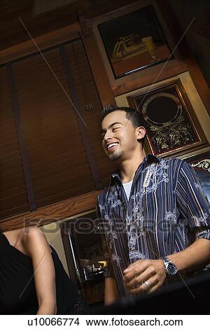 Young Hispanic man laughing and drinking beer at pub. View Large Photo Image Picture - Young Hispanic man laughing and drinking beer at pub.. Fotosearch