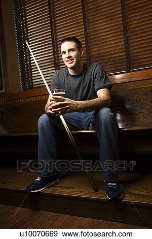 Young man holding billiards cue while hanging out at pub. View Large Photo Image Stock Photo - Young man holding billiards cue while hanging out at pub.. Fotosearch