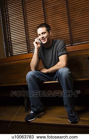 Young man talking on cellphone while hanging out at pub. View Large Photo Image Stock Image - Young man talking on cellphone while hanging out at pub.. Fotosearch