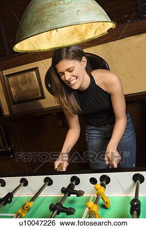 Young woman smiling while playing foosball game at pub. View Large Photo Image Stock Photograph - Young woman smiling while playing foosball game at pub.. Fotosearch