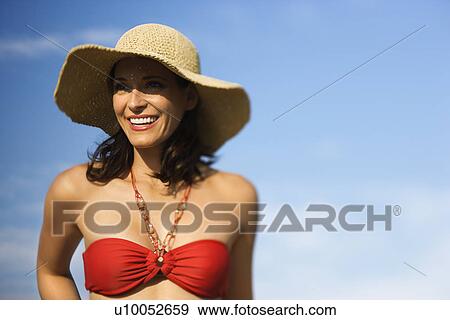 Stock Photo - Caucasian mid-adult female in swimsuit and straw hat.. Fotosearch