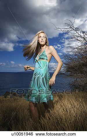 Caucasian young adult blond woman standing in field on coast with hair swinging out. View Large Photo Image Stock Photograph - Caucasian young adult blond woman standing in field on coast with hair swinging out.. Fotosearch