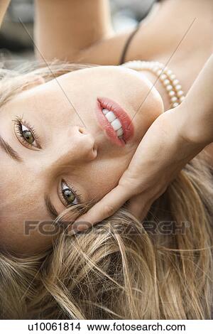 Close-up portrait of Caucasian young adult woman lying with hand to face making eye contact. View Large Photo Image Picture - Close-up portrait of Caucasian young adult woman lying with hand to face making eye contact.. Fotosearch