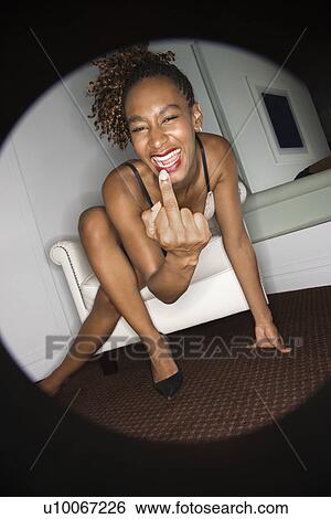 Stock Photograph - Young sexy African-American woman kneeling on floor laughing and smiling showing middle finger.. Fotosearch