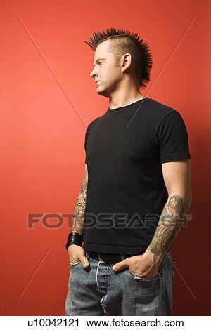 Caucasian man with mohawk and tattoos standing with hands in pockets against orange background. View Large Photo Image Stock Image - Caucasian man with mohawk and tattoos standing with hands in pockets against orange background.. Fotosearch