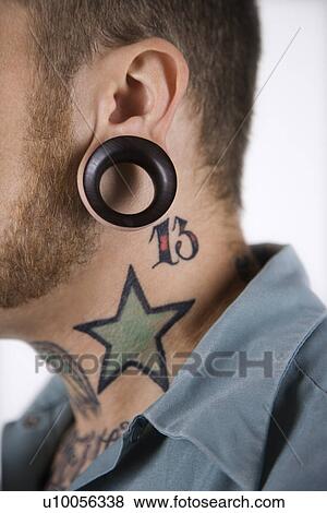 Stock Photo - Caucasian mid-adult man with tattoos and piercings.. Fotosearch