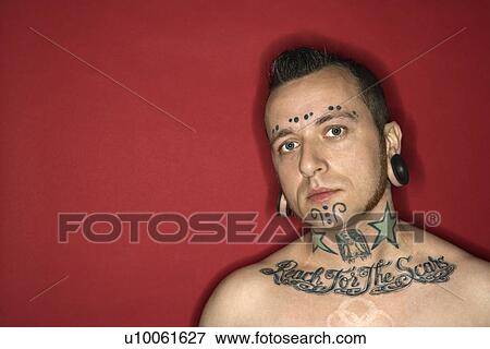 Stock Photo - Caucasian mid-adult man with tattoos and piercings.. Fotosearch